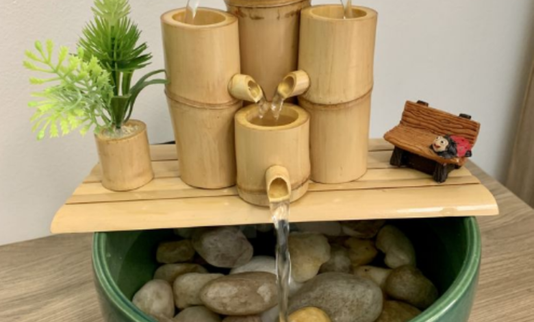 Fonte de bambu com água fluindo e plantinha decorativa.