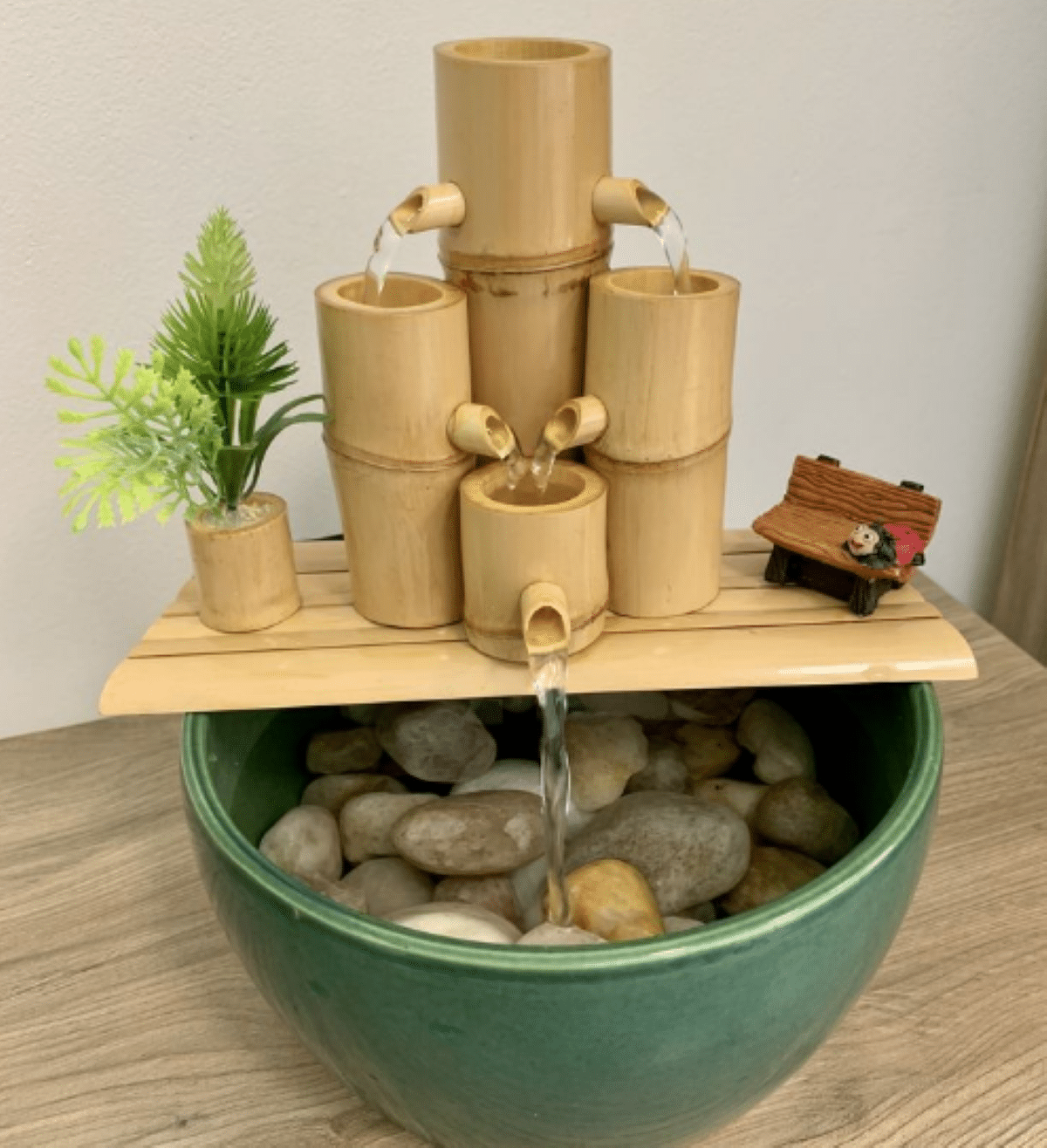 Fonte de bambu com água fluindo e plantinha decorativa.