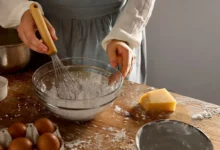 Imagem de uma pessoa mexendo ingredientes secos em uma tigela, ilustrando a preparação de receitas com bicarbonato de sódio e fermento em pó.