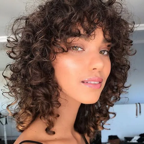 Cabelo cacheado com corte bob desfiado, estilo natural e volumoso