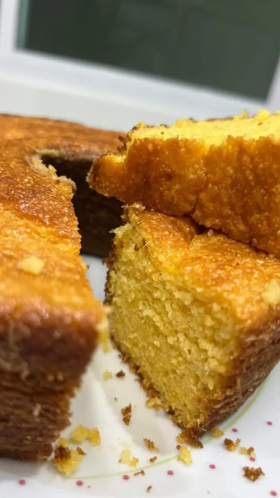 Bolo de cenoura dourado com uma fatia cortada, destacando sua textura macia e úmida