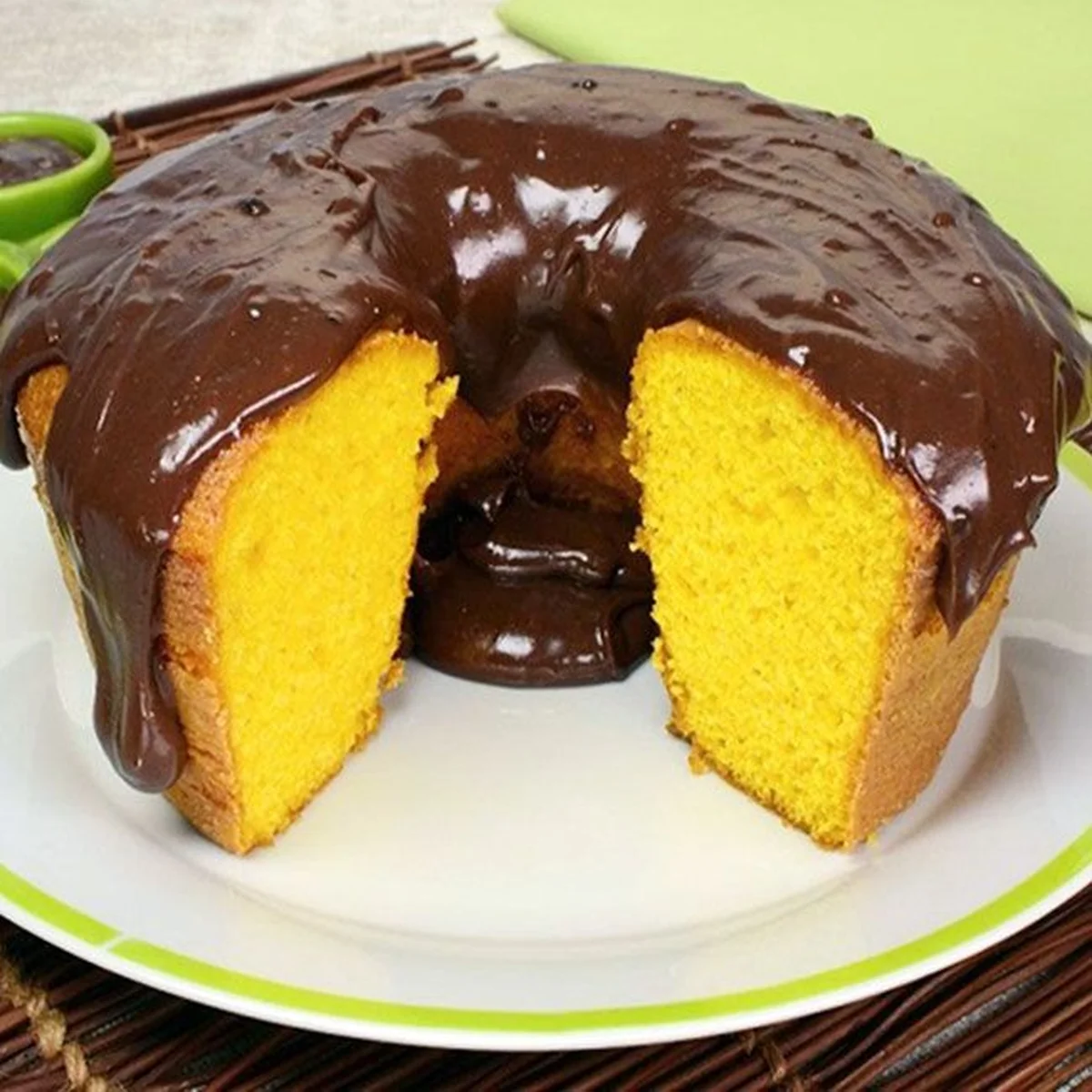 Bolo de fubá coberto com ganache de chocolate, com o interior fofo e dourado visível.