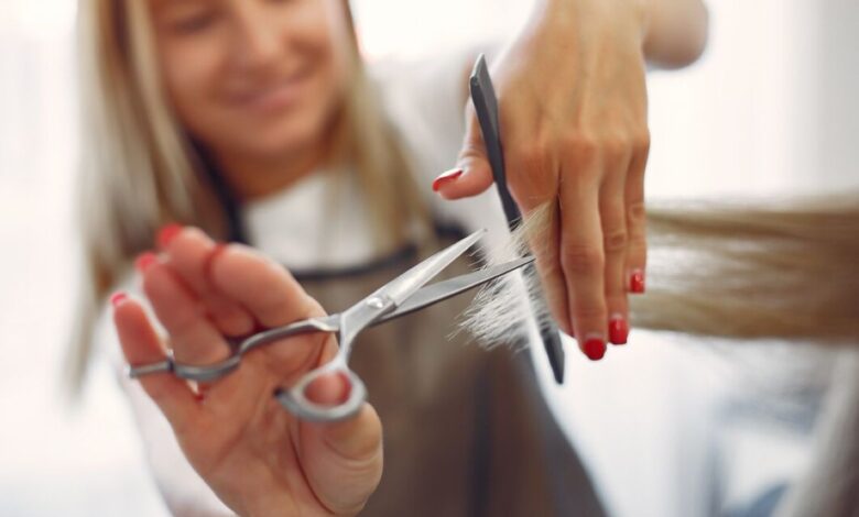 Cabeleireira cortando cabelo longo com precisão em um salão de beleza.