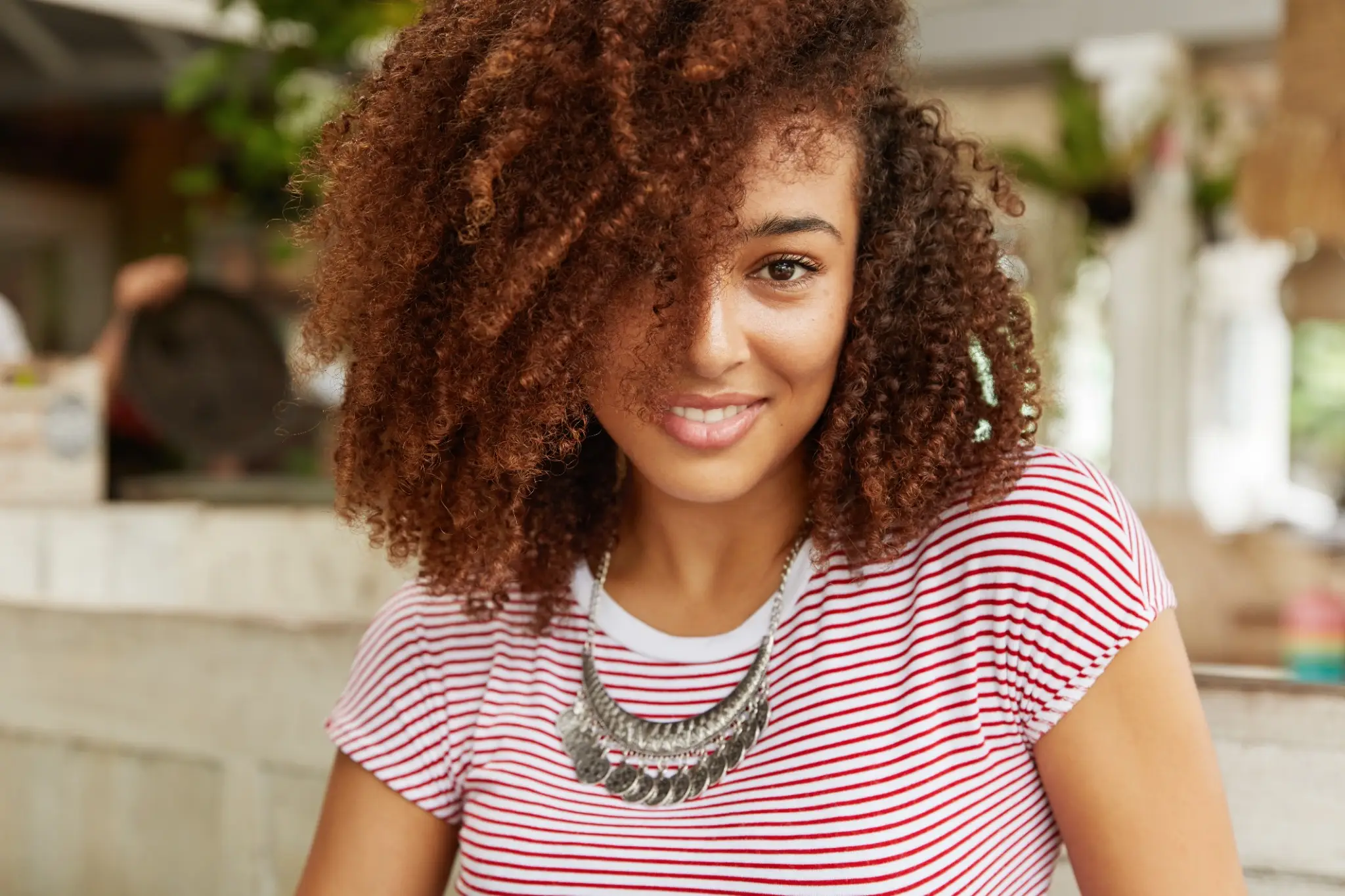 Mulher com cabelo cacheado volumoso, exemplo de corte para valorizar os cachos.