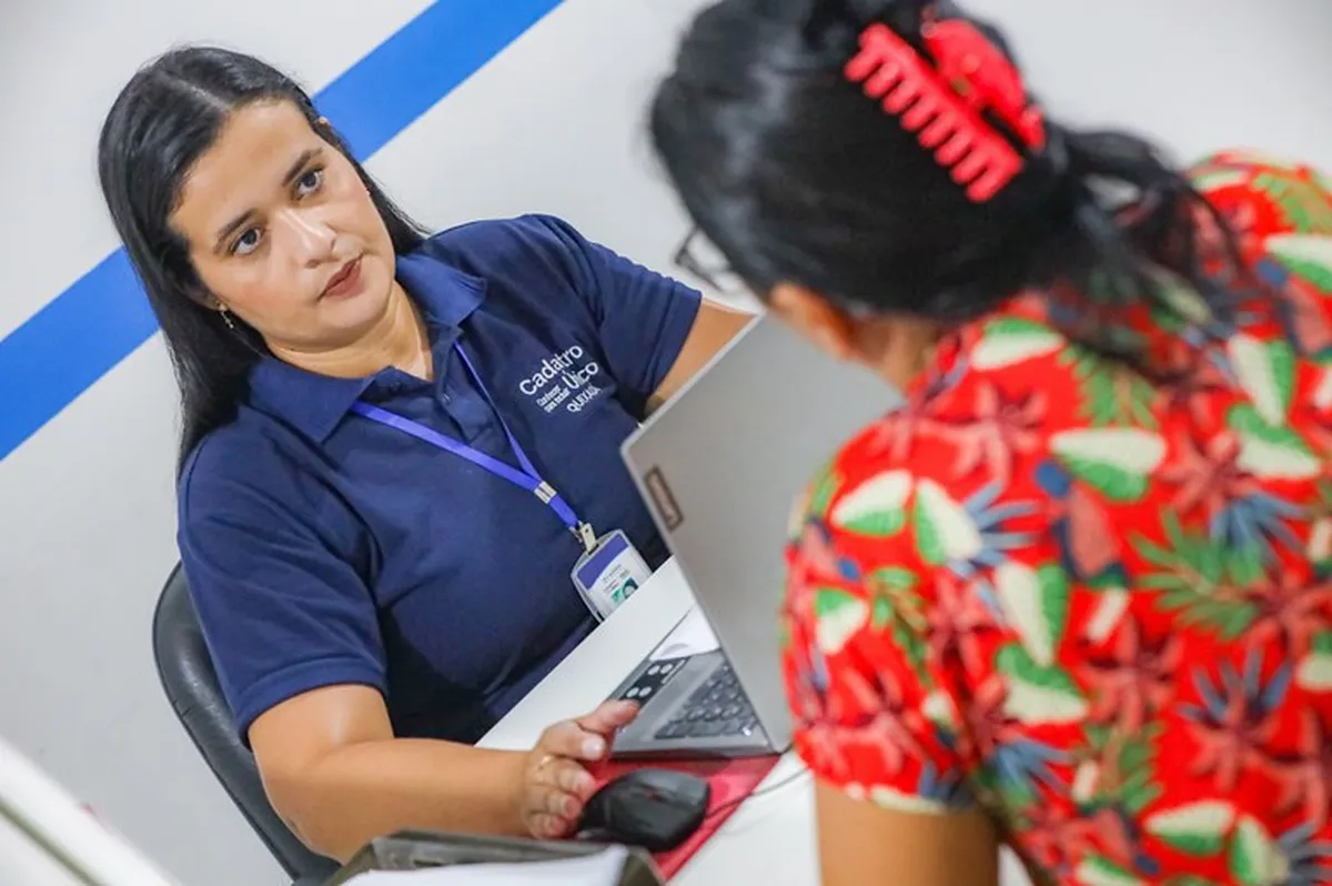 Atendente capacitada do Cadastro Único ajudando um beneficiário em atendimento.