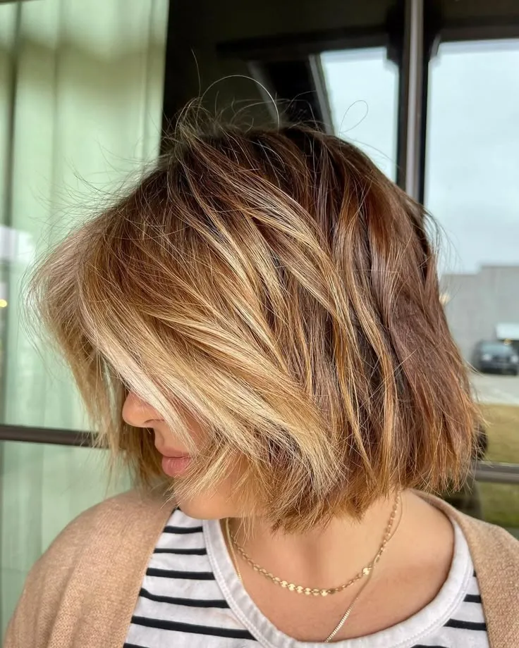 Corte choppy bob na altura do queixo com luzes loiras e camadas sutis.