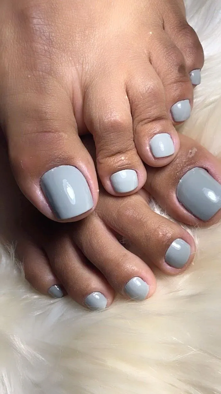 Unhas dos pés pintadas com esmalte cinza lavanda, transmitindo suavidade e elegância