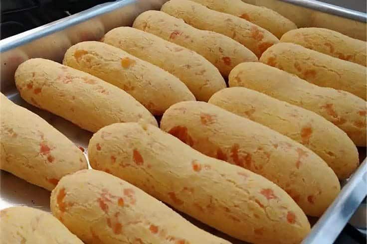 Biscoitos salgados em formato de pão de queijo, com pedaços de queijo visíveis.