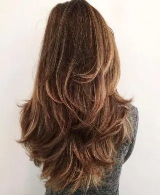 Mulher com corte butterfly cut, cabelo longo e com camadas leves, moderno e fácil de manter.