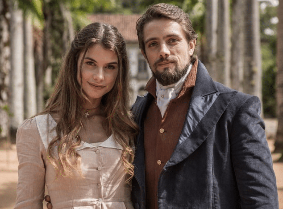 Casal protagonista de novela de época com temática espírita, vestindo trajes do século XIX.