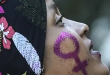 Mulher com símbolo feminino brilhante pintado no rosto, representando empoderamento.