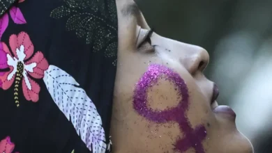 Mulher com símbolo feminino brilhante pintado no rosto, representando empoderamento.