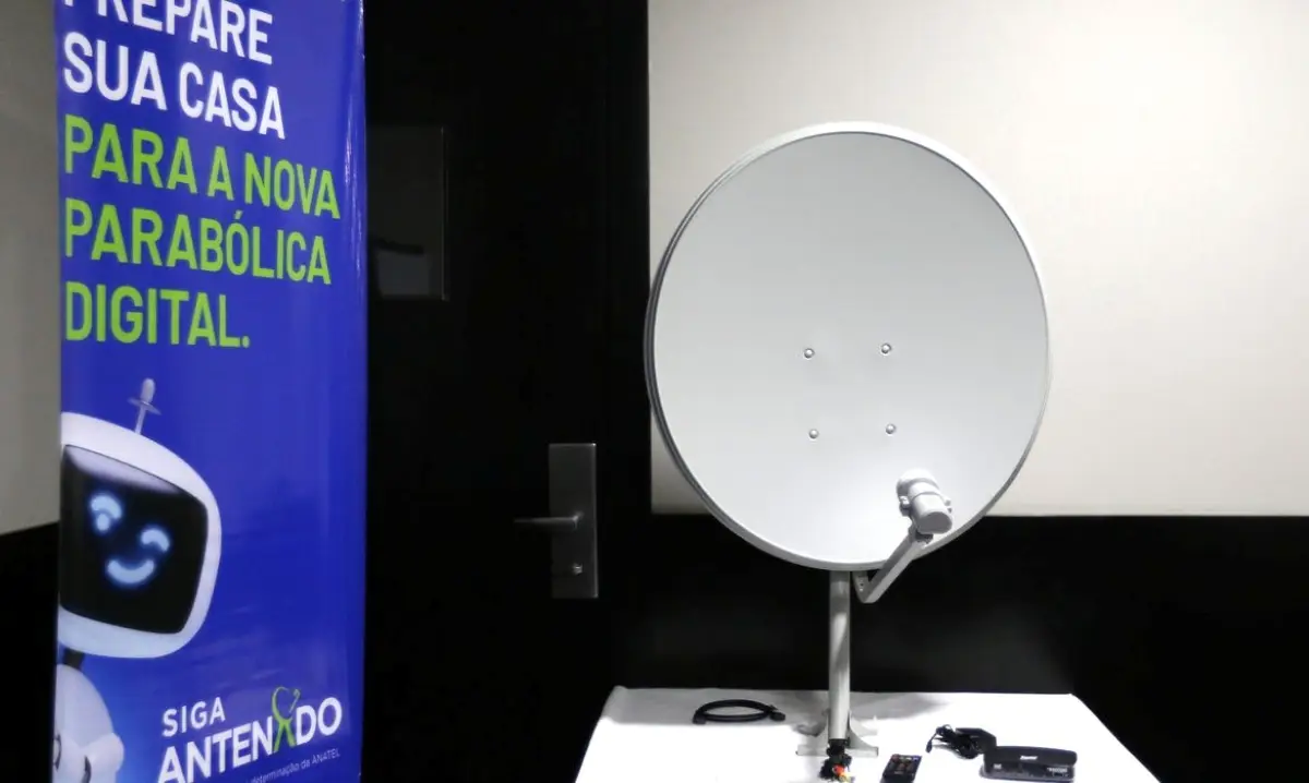 Imagem de um kit de antena parabólica digital, com a antena, controle e acessórios, promovendo o programa gratuito de distribuição para famílias.