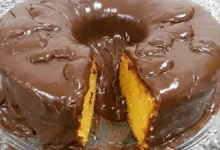 Bolo de cenoura com calda de chocolate crocante, mostrando uma fatia com a textura macia do interior.