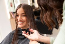 Mulher sorrindo durante corte de cabelo em salão de beleza.