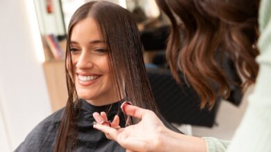 Mulher sorrindo durante corte de cabelo em salão de beleza.