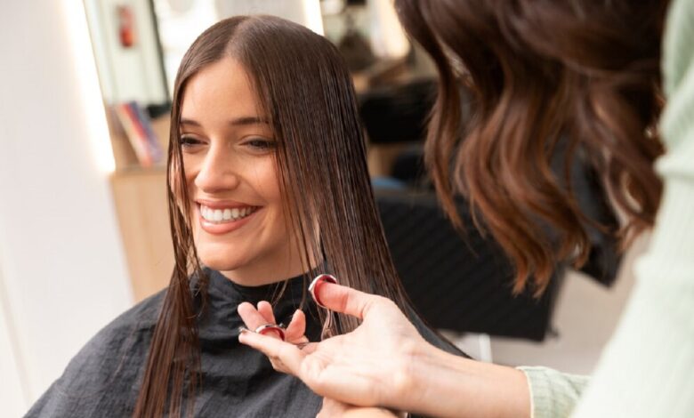 Mulher sorrindo durante corte de cabelo em salão de beleza.