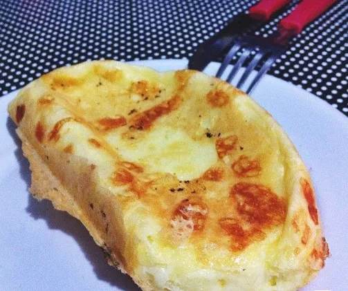 Pão de queijo na frigideira com casquinha dourada servido em um prato branco.