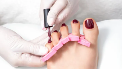 Imagem de uma pedicure sendo feita em um pé com esmalte roxo escuro, representando tendências de cores de esmalte para os pés em 2025.