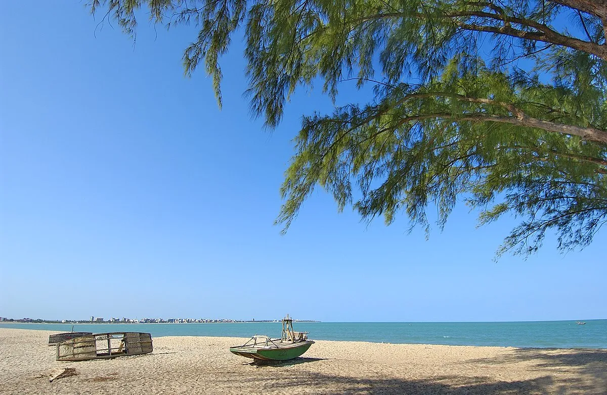 Vista da Praia do Bessa, com uma paisagem tranquila e uma embarcação na areia.