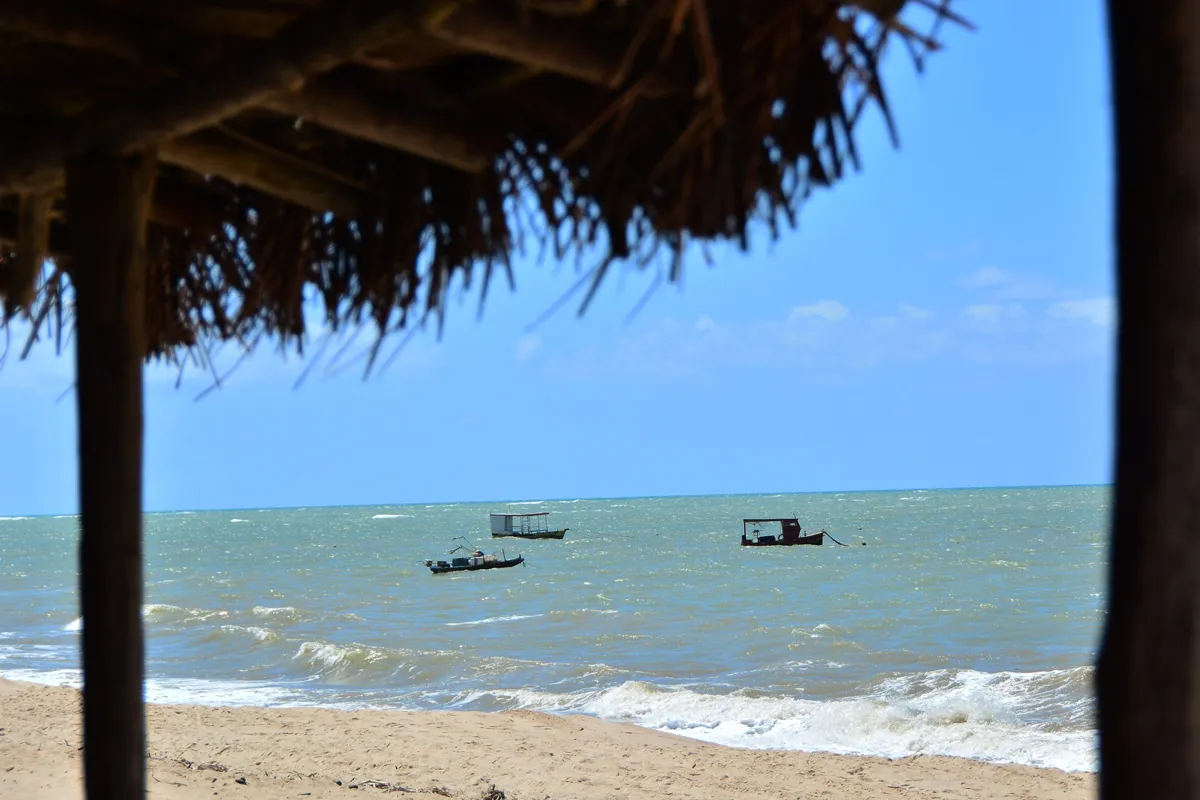 Vista da Praia do Jacarapé, com barcos de pesca ao longe e a tranquilidade do mar.