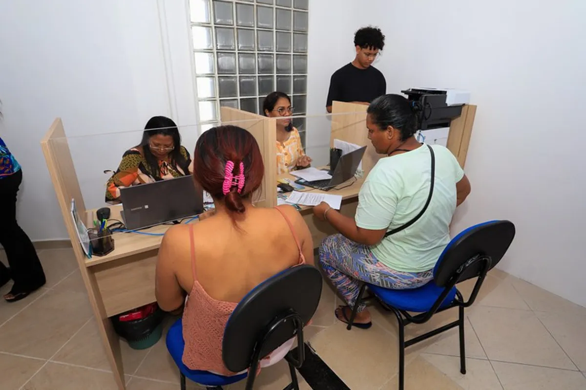 Atendimento no posto de atualização dos dados do Bolsa Família, com pessoas sendo atendidas por funcionários.