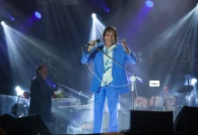 Roberto Carlos se apresentando no palco em um show, vestindo um terno azul e segurando um microfone