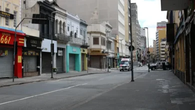 Rua com comércios fechados e pouca movimentação, representando um feriado nacional.