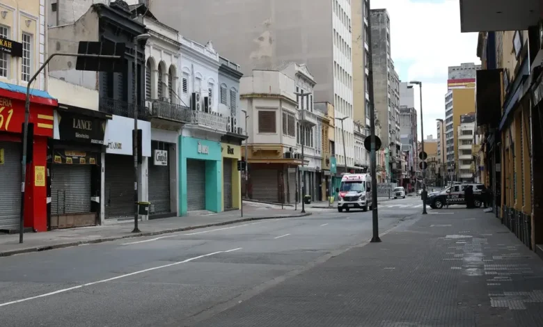 Rua com comércios fechados e pouca movimentação, representando um feriado nacional.