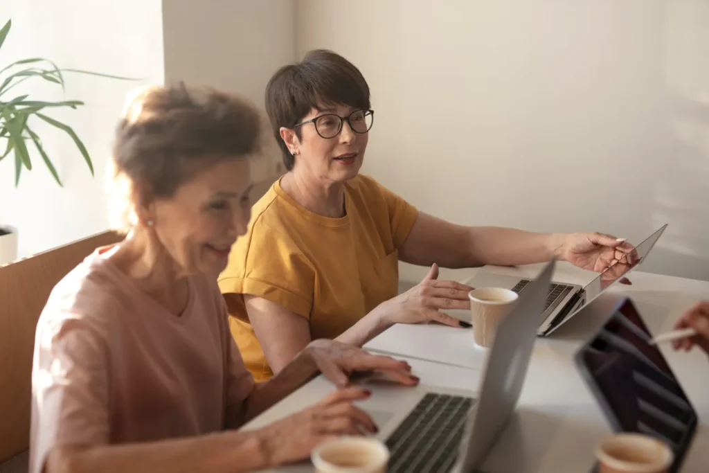 Duas mulheres idosas trabalhando juntas em um escritório, destacando a importância da colaboração e valorização da mão de obra idosa