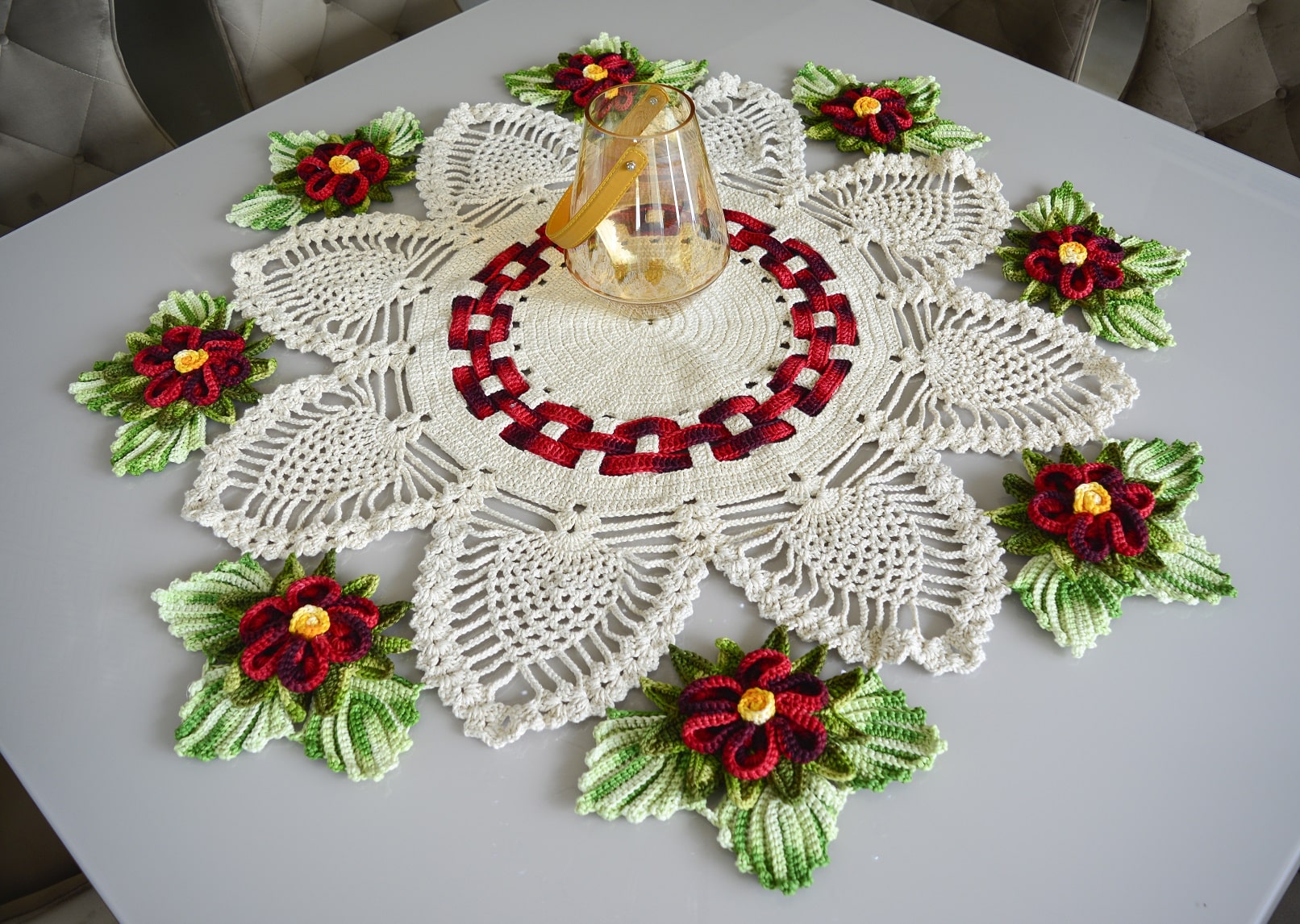 Centro de mesa em crochê elegante com flores vermelhas e verdes, ideal para decoração sofisticada.