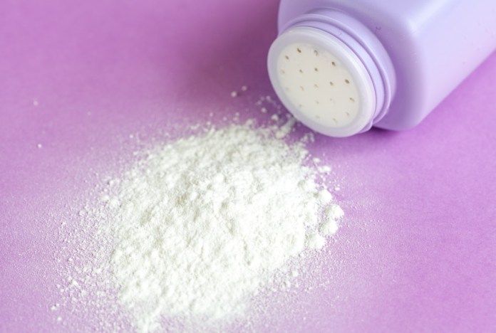 Pó de talco derramado ao lado de um recipiente roxo, usado para disfarçar a oleosidade no cabelo.