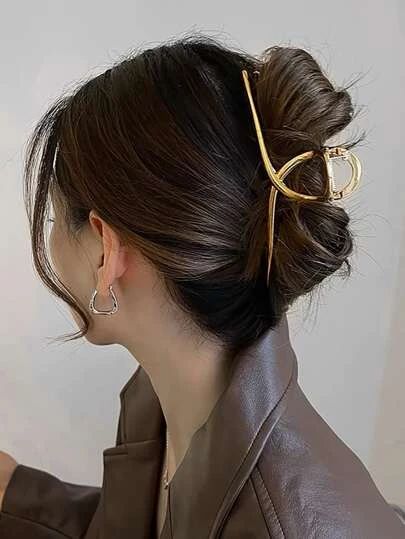 Mulher com cabelo preso em um coque elegante, adornado com um acessório dourado.