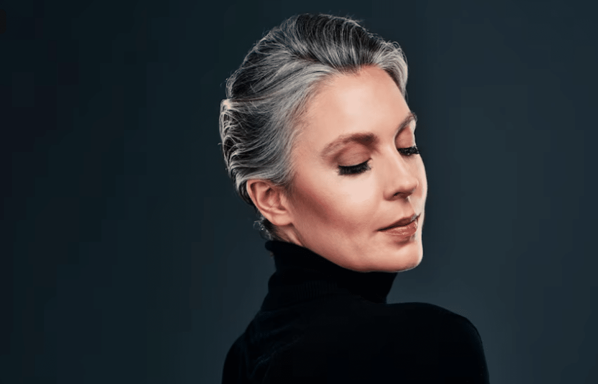 Mulher com cabelo grisalho estiloso em corte moderno, mostrando confiança e elegância.