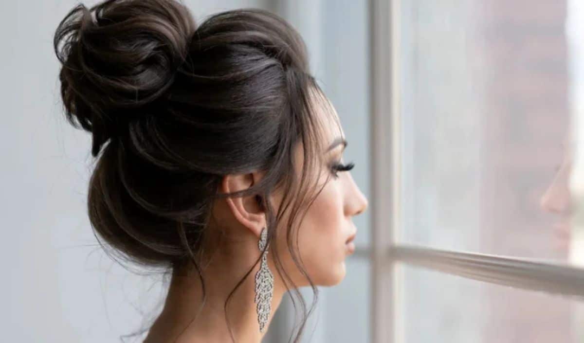 "Mulher com coque alto, penteado sofisticado e elegante, observando pela janela.