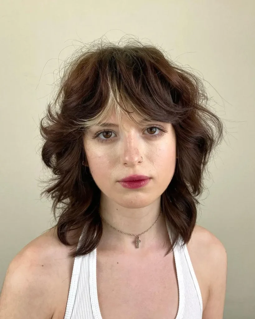 Mulher com corte de cabelo shaggy, um estilo perfeito para rostos ovais, com camadas e movimento.