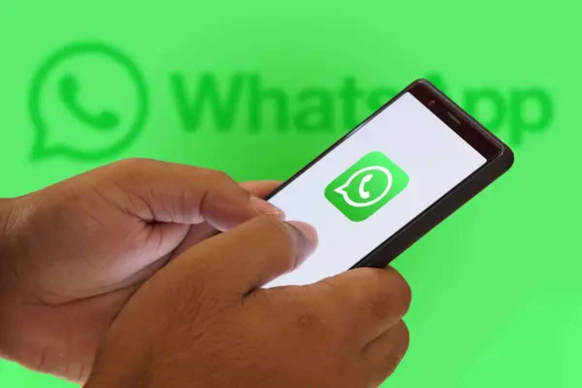Pessoa segurando um celular com o ícone do WhatsApp na tela