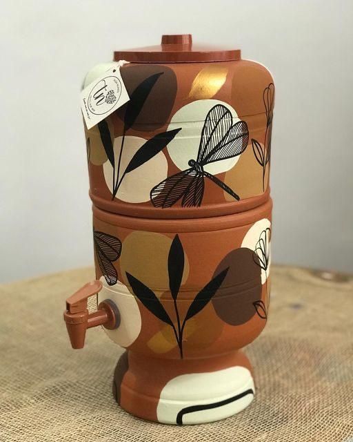 Filtro de barro decorado com design moderno, com ilustrações abstratas em cores quentes.