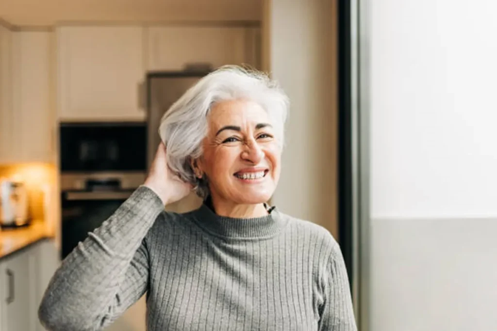 Mulher sorridente com cabelo grisalho curto e elegante, em ambiente iluminado