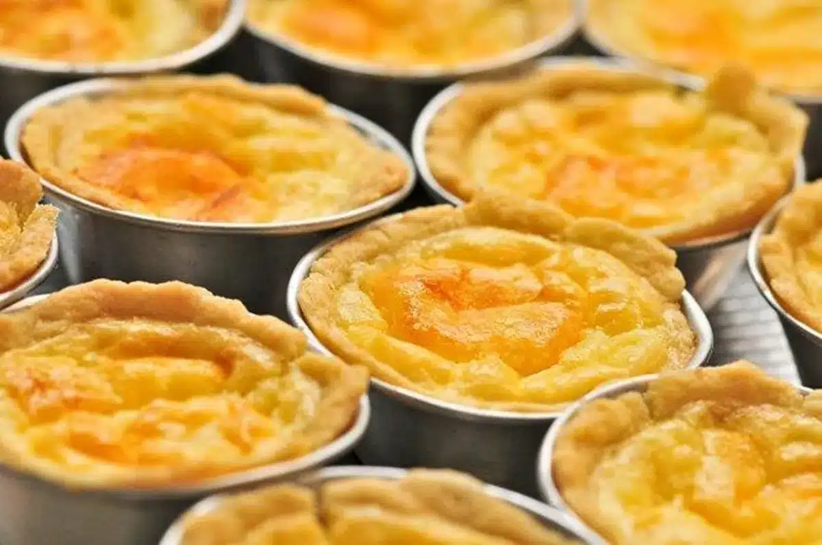 Empadinhas de queijo douradas em forminhas de alumínio, recém-assadas