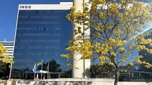 Fachada do edifício do INSS com bandeira do Brasil e árvores ao redor, representando a resposta oficial do Instituto