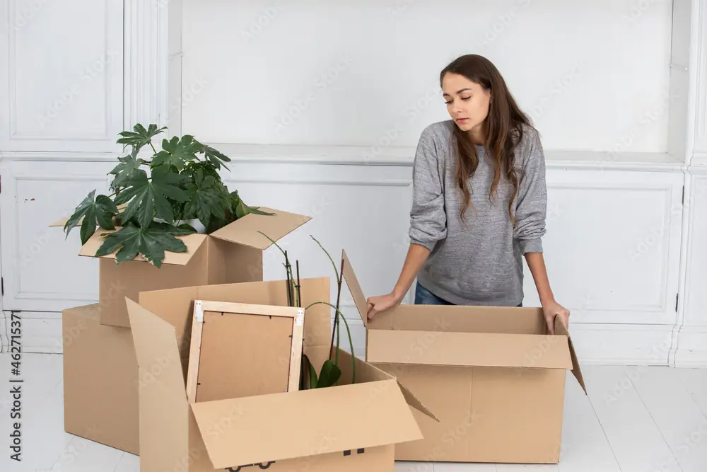 Mulher organizando caixas de papelão durante mudança ou reorganização da casa.