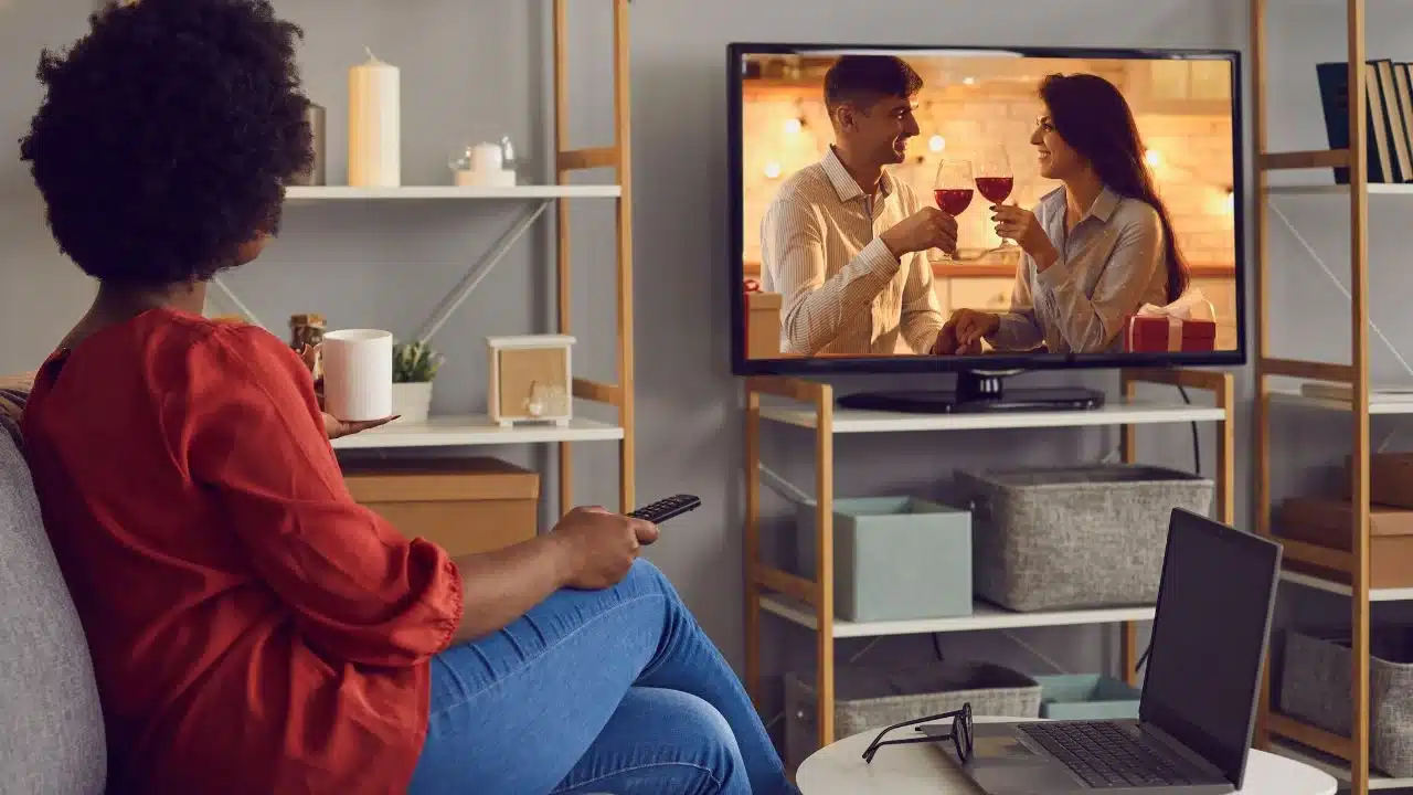 Pessoa assistindo a uma novela turca de comédia na TV, relaxando com uma xícara de chá ou café