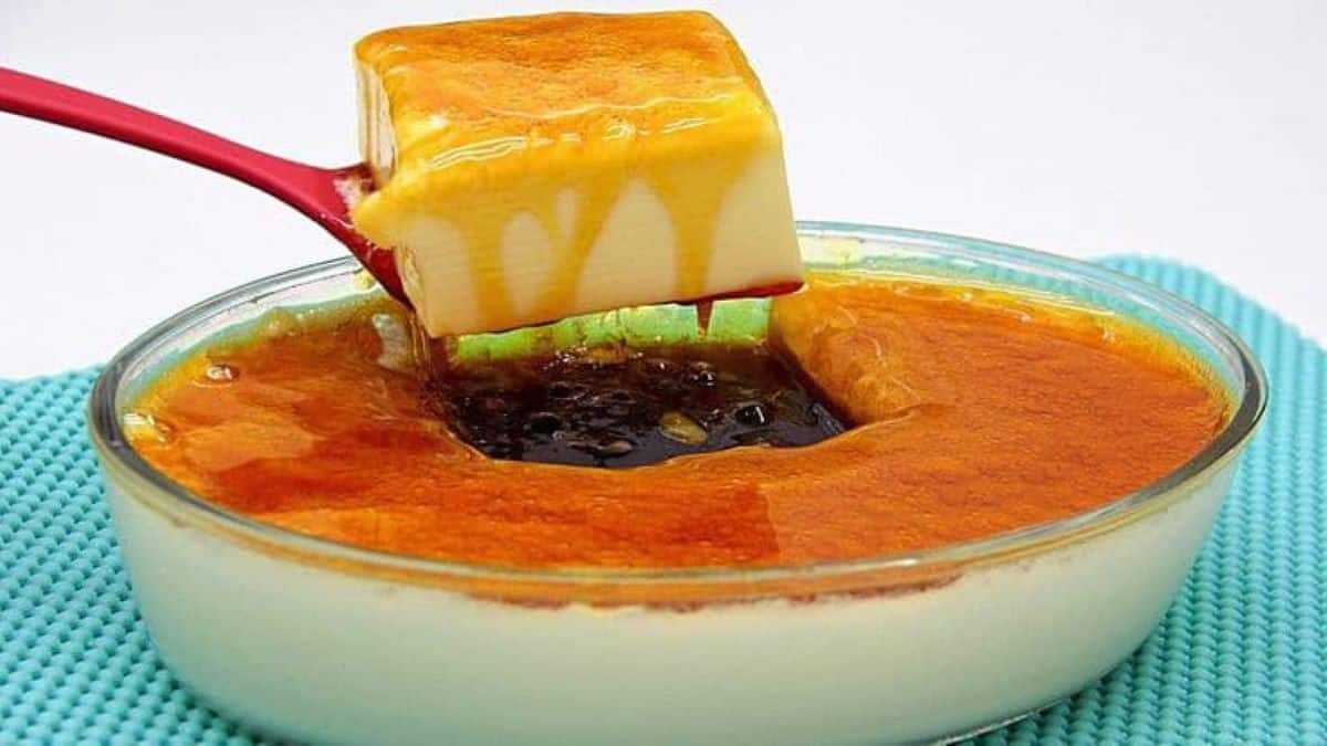 pedaço de pudim de travessa sendo servido com calda brilhante.