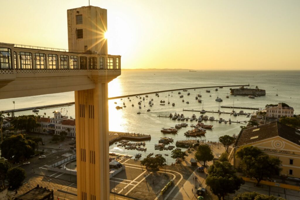 Vista panorâmica do Elevador Lacerda em Salvador, com o sol brilhando sobre o mar.