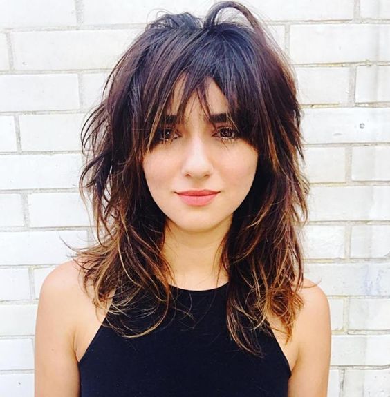 Mulher com cabelo médio e franja desfiada, em estilo moderno e descontraído