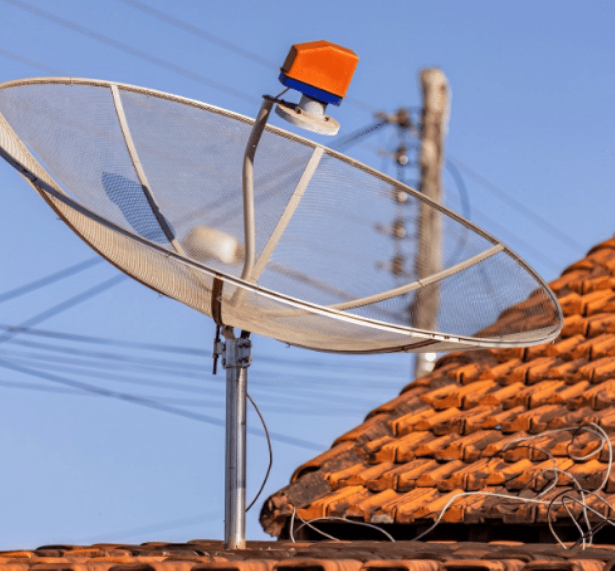 Antena parabólica antiga em telhado residencial prestes a ser substituída devido ao desligamento do sinal tradicional.