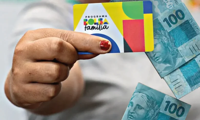 Cartão do Programa Bolsa Família com cédulas de 100 reais ao fundo