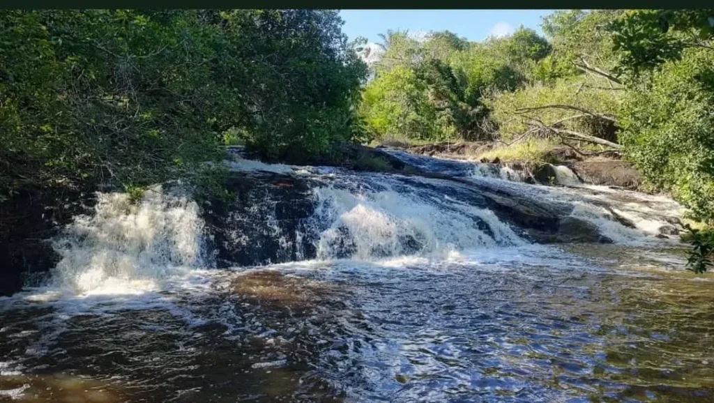 Cachoeira Dona Zilda, com águas rolando por pedras em um cenário natural exuberante, próximo a Salvador
