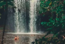 Pessoas se banhando na base de uma cachoeira rodeada por vegetação em uma área próxima a Salvador